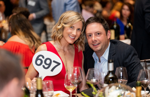 Couple at table holding bid sign