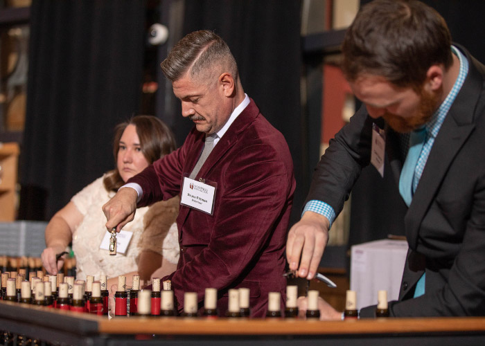 Woman and two men uncorking wine bottles